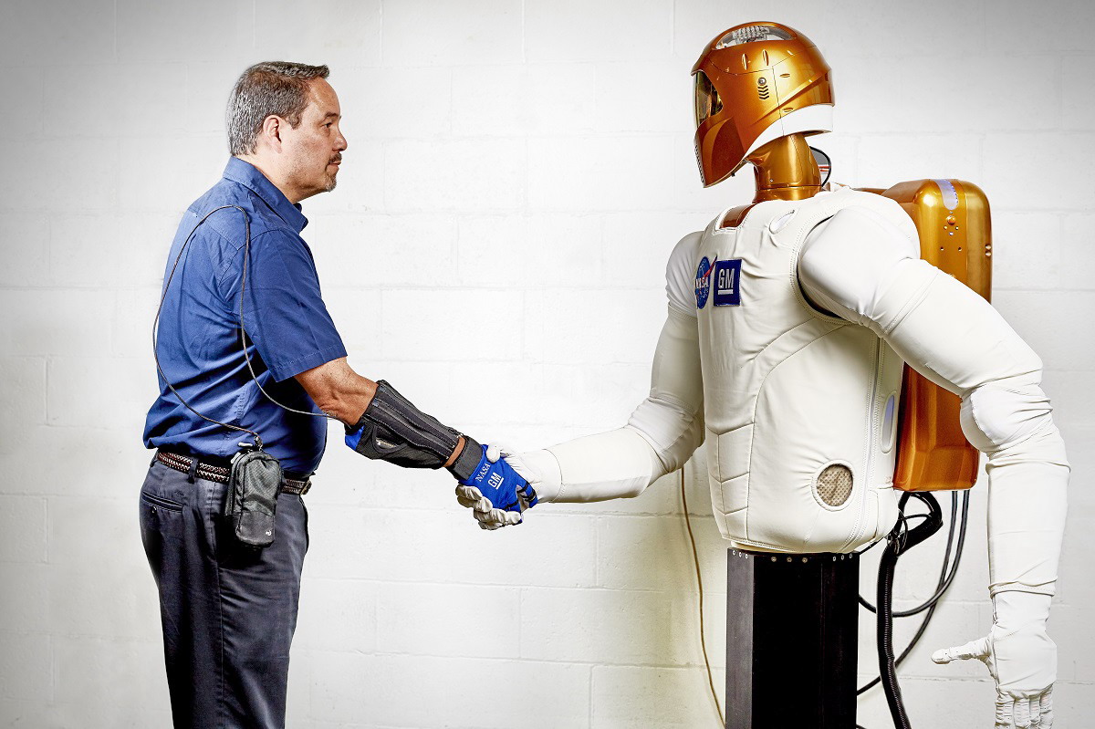 Handshake - Marty Linn, General Motors manager of advanced technology and principal engineer for robotics, shakes hands with Robonaut 2 (R2), a humanoid robot developed by GM and NASA during a nine-year collaboration that also led to development of the RoboGlove, an exo-muscular device that enhances strength and grip through leading-edge sensors, actuators and tendons that are comparable to the nerves, muscles and tendons in a human hand. GM is licensing the RoboGlove intellectual property to Bioservo Technologies AB, a Swedish medical technologies company that will combine RoboGlove with its owner patented SEM glove technology.